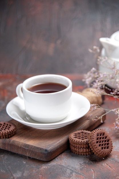 Vista frontal de la taza de té con galletas en la mesa oscura galleta oscura
