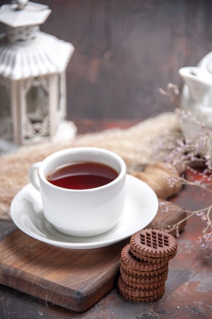 Vista frontal de la taza de té con galletas en la mesa oscura galleta oscura