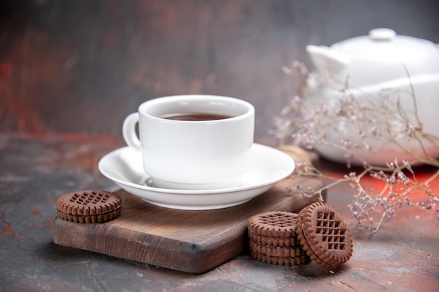 Vista frontal de la taza de té con galletas en la mesa oscura galleta oscura