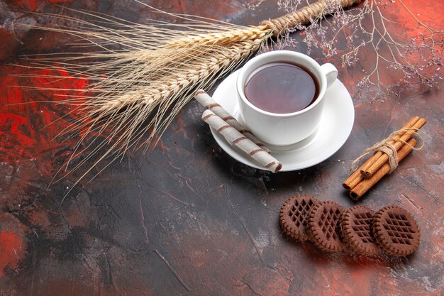 Vista frontal de la taza de té con galletas en la mesa oscura té oscuro