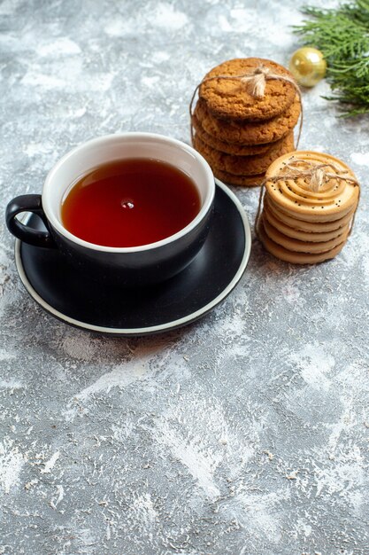 Vista frontal de una taza de té con galletas sobre fondo blanco.