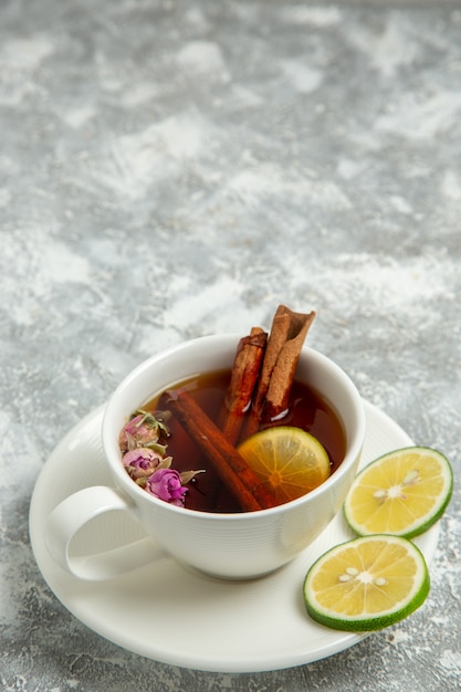 Vista frontal de la taza de té con limón y canela en la superficie blanca bebida de té dulce azúcar caliente