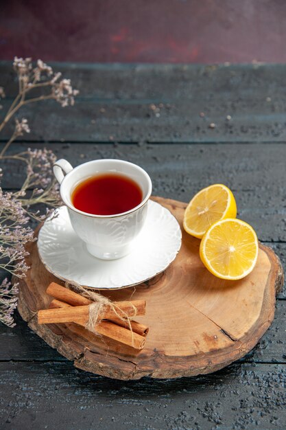 Vista frontal de la taza de té con limón sobre fondo oscuro