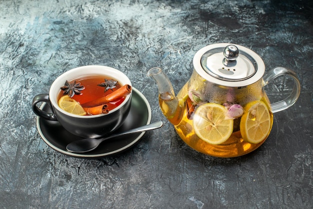Vista frontal taza de té con limón y tetera sobre fondo gris ceremonia de desayuno de frutas foto en color comida mañana