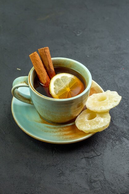Vista frontal de una taza de té con rodajas de limón sobre una superficie oscura