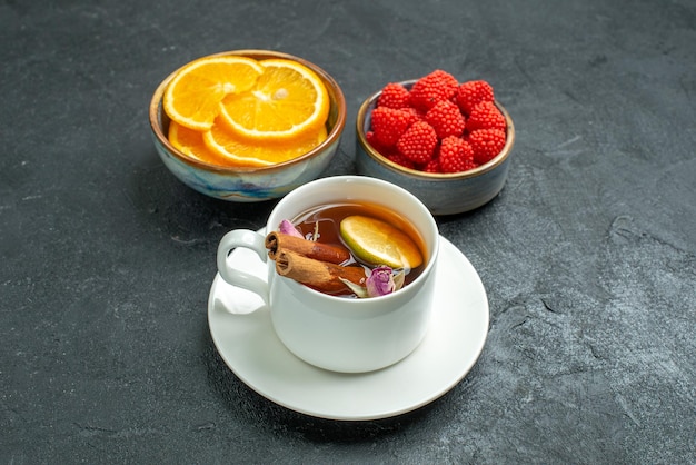 Foto gratuita vista frontal de una taza de té con rodajas de naranja y confituras en té cítrico de frutas de superficie oscura