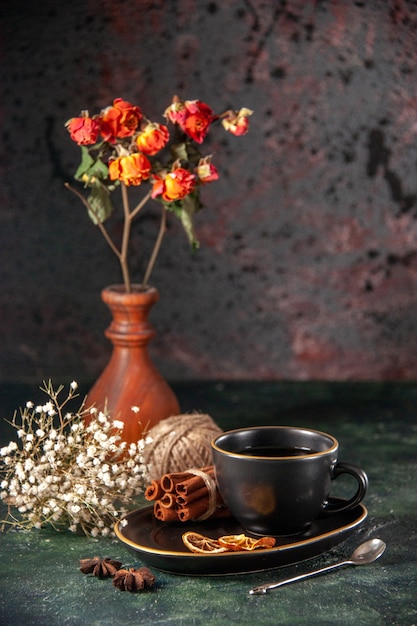 Vista frontal de la taza de té en la taza y el plato negro con canela en la pared oscura ceremonia de azúcar de cristal desayuno color pastel dulce