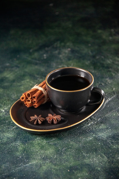 Vista frontal de la taza de té en la taza y el plato negro sobre la superficie oscura ceremonia del azúcar pastel de desayuno postre dulce color