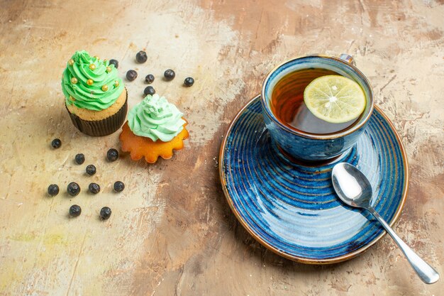 Vista frontal de una taza de té con tortas dulces en la mesa marrón