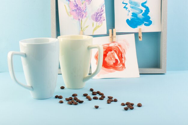 Una vista frontal de tazas blancas con colgantes y semillas de café.