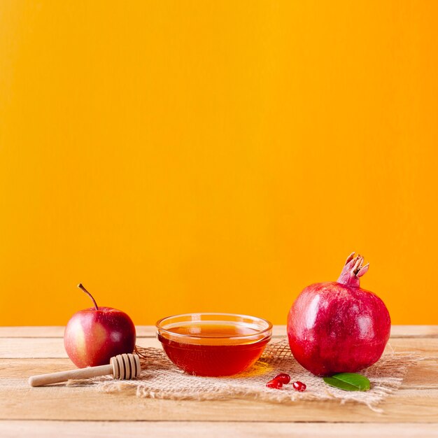Vista frontal tazón de miel con cucharón y frutas