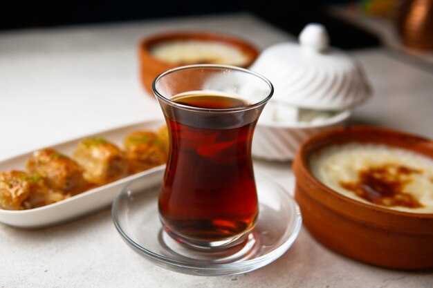 Vista frontal de té en un vaso armudu con baklava y azúcar sobre la mesa