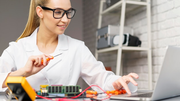 Foto gratuita vista frontal del técnico femenino con electrónica y portátil