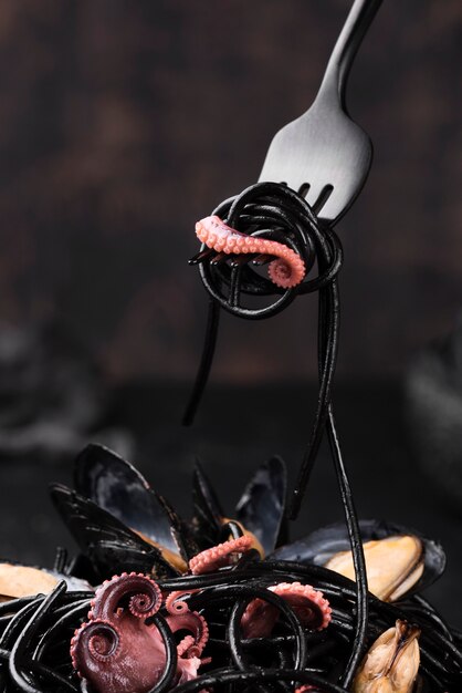 Vista frontal del tenedor con pasta negra y calamares