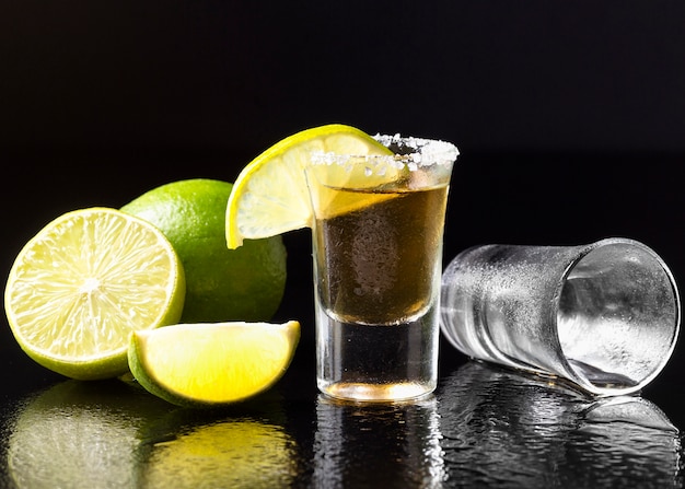 Vista frontal de tequila dorado con limón y sal