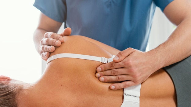 Vista frontal del terapeuta osteopático comprobando la espalda del paciente femenino