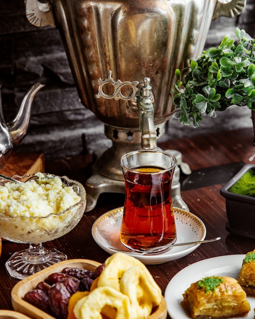 Vista frontal de una tetera de samovar con una taza de té con frutos secos