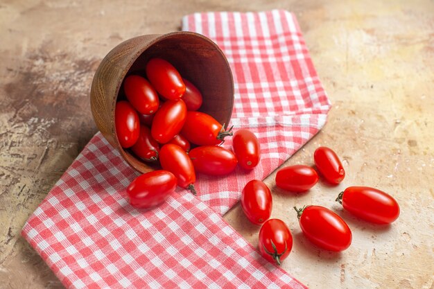 Vista frontal de los tomates cherry esparcidos del cuenco una toalla de cocina en ámbar