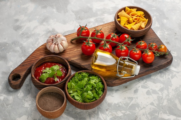 Vista frontal de tomates cherry frescos con condimentos y verduras en la superficie blanca comida vegetal ensalada saludable de alimentos