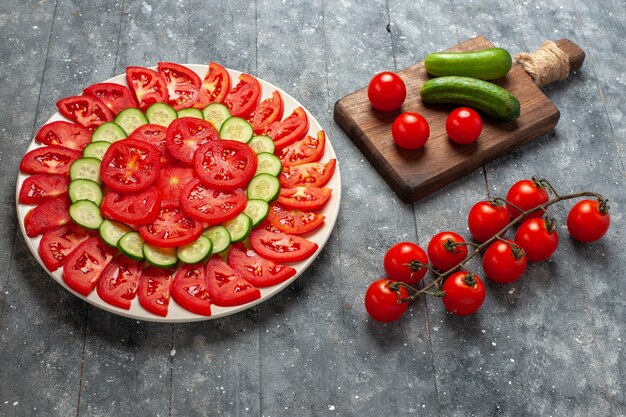 Vista frontal de tomates frescos en rodajas ensalada de elegante diseño en espacio rústico gris