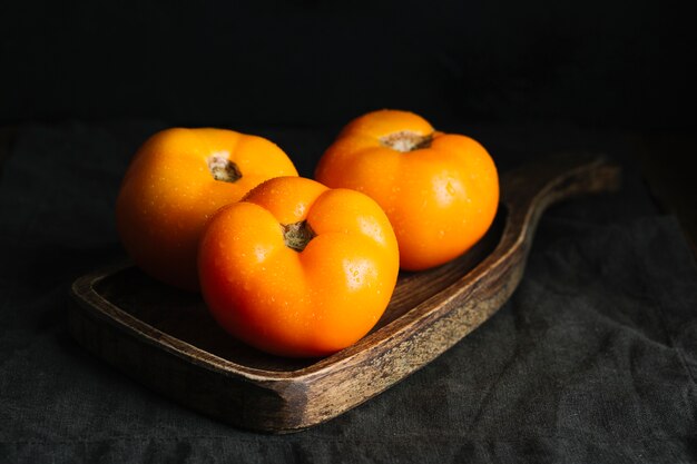 Vista frontal de tomates naranjas adultos en tabla de cortar