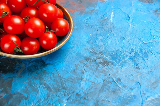 Vista frontal de los tomates rojos frescos dentro de la placa sobre el cuadro azul