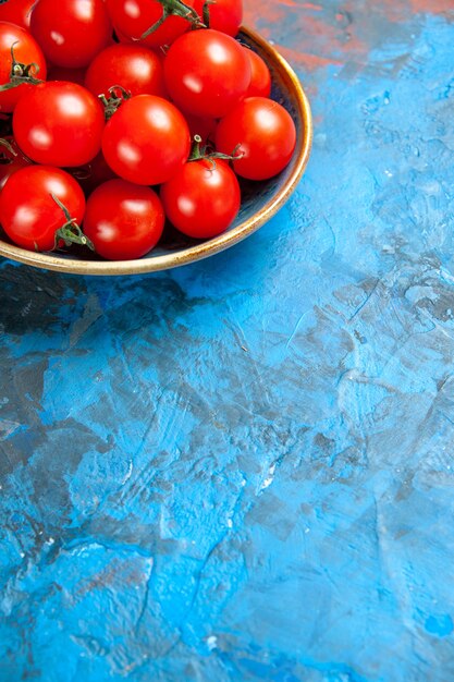 Vista frontal de los tomates rojos frescos dentro de la placa sobre el cuadro azul