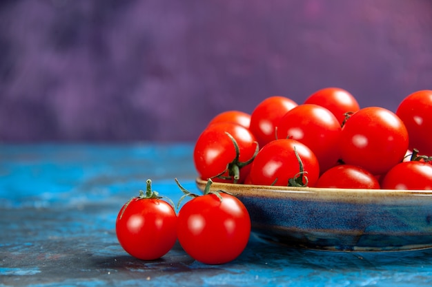 Vista frontal de los tomates rojos frescos dentro de la placa sobre el cuadro azul