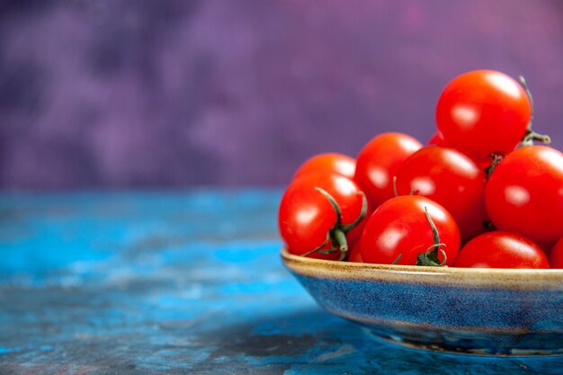 Vista frontal de los tomates rojos frescos dentro de la placa sobre el cuadro azul