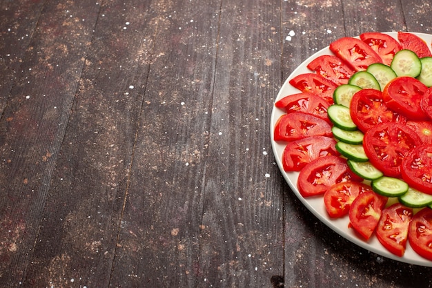 Foto gratuita vista frontal de tomates rojos frescos ensalada fresca en rodajas en el escritorio marrón