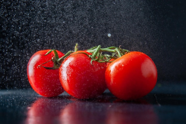 Vista frontal de tomates rojos frescos en la oscuridad