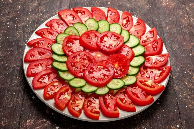 Vista frontal de tomates rojos frescos en rodajas ensalada fresca en espacio marrón