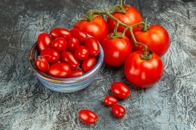 Vista frontal de tomates rojos frescos sobre un fondo claro oscuro