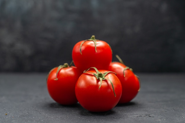 Vista frontal de tomates rojos frescos sobre fondo oscuro ensalada de fotos en color de comida madura