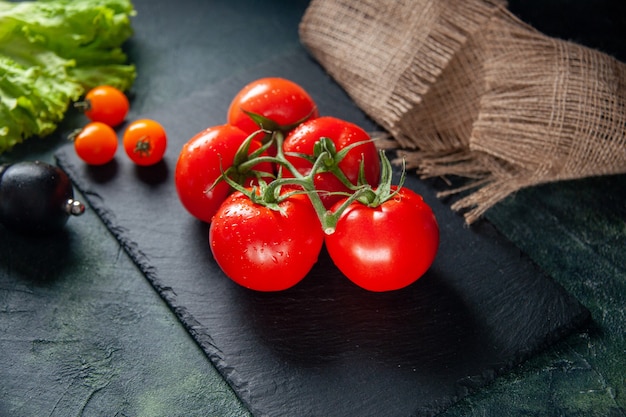 Vista frontal de tomates rojos frescos sobre fondo oscuro