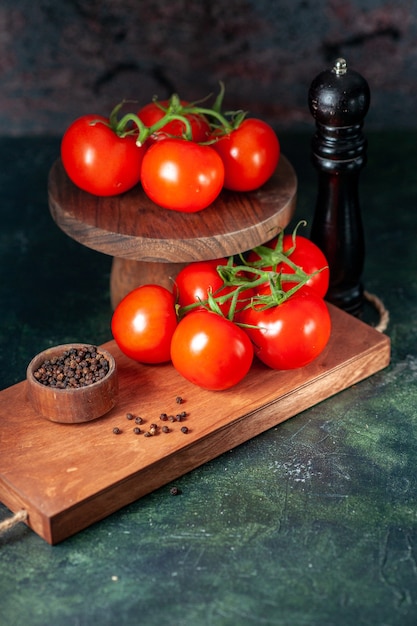 Vista frontal de tomates rojos frescos sobre fondo oscuro