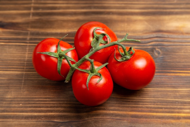 Vista frontal de tomates rojos verduras maduras en el escritorio de madera marrón ensalada de dieta fresca madura roja