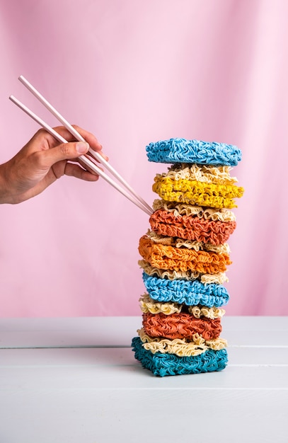 Foto gratuita vista frontal de la torre de ramen colorido y mano con palillos