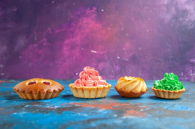 Vista frontal de la torta de frambuesa tartas pequeñas galletas en el espacio libre de la mesa rosa azul