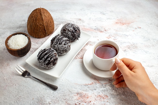 Vista frontal de tortas de chocolate con una taza de té en el escritorio blanco pastel de chocolate galleta galletas dulces de azúcar