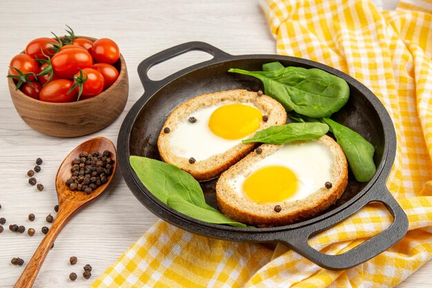 Vista frontal tostadas de huevo dentro de la sartén sobre el fondo blanco almuerzo comida té plato pan color desayuno