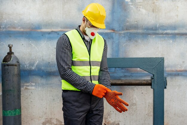 Vista frontal del trabajador con casco poniéndose guantes protectores