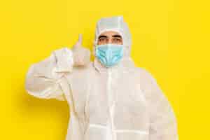 Foto gratuita vista frontal del trabajador científico masculino en traje blanco de protección especial con máscara en el escritorio amarillo trabajador científico química científica peligro de color