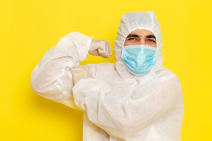 Foto gratuito vista frontal del trabajador científico masculino en traje de protección especial y con máscara flexionando en la pared amarilla clara