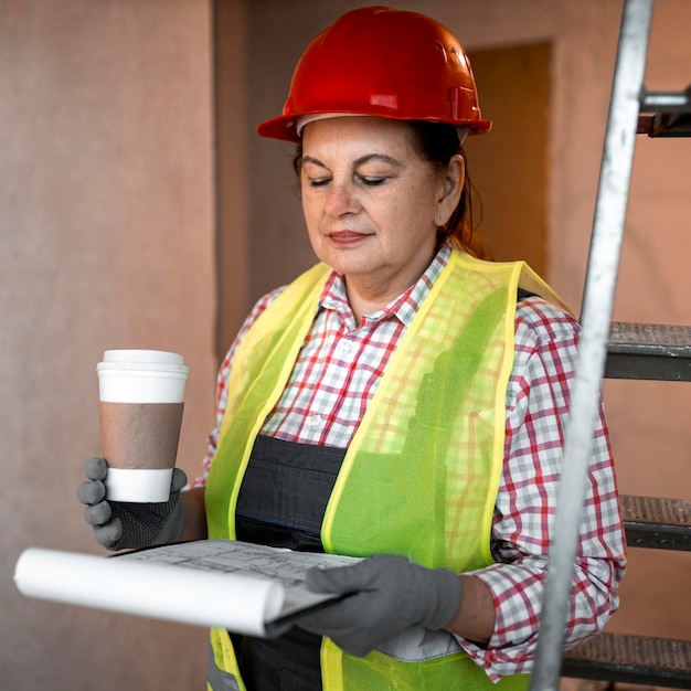 Foto gratuita vista frontal del trabajador de la construcción femenina con café y plan