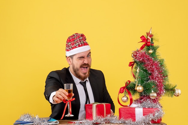 Vista frontal del trabajador masculino celebrando la Navidad con champán en amarillo