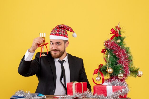 Vista frontal del trabajador masculino celebrando la Navidad con champán en amarillo