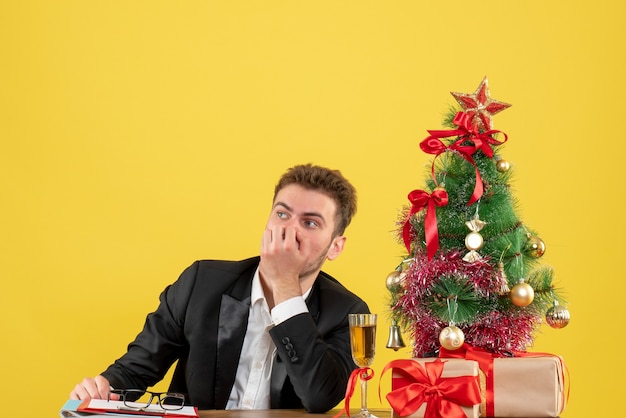Vista frontal del trabajador masculino detrás de su lugar de trabajo con regalos en amarillo