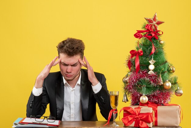 Vista frontal del trabajador masculino detrás de su lugar de trabajo con regalos en amarillo