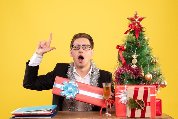 Vista frontal trabajador masculino sentado y celebrando la Navidad